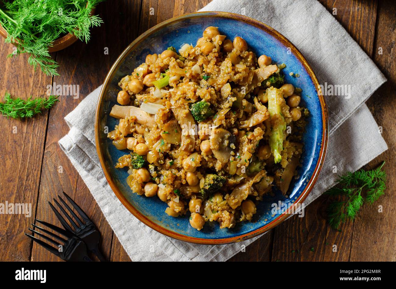 Quinoa con ceci, funghi e broccoli, pasto sano, cibo vegetariano, Sfondo rustico scuro Foto Stock