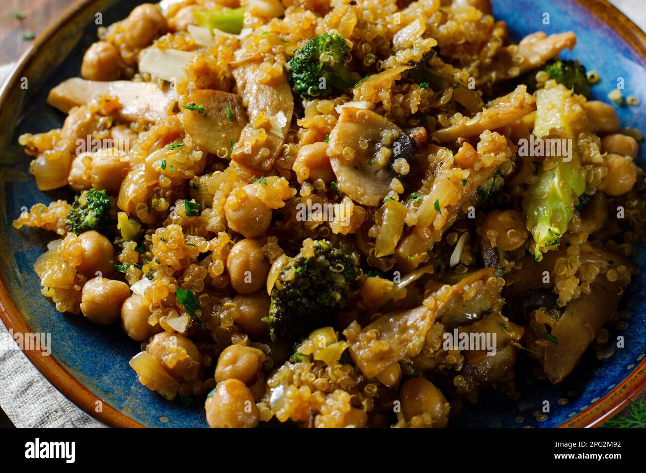 Quinoa con ceci, funghi e broccoli, pasto sano, cibo vegetariano, Sfondo rustico scuro Foto Stock