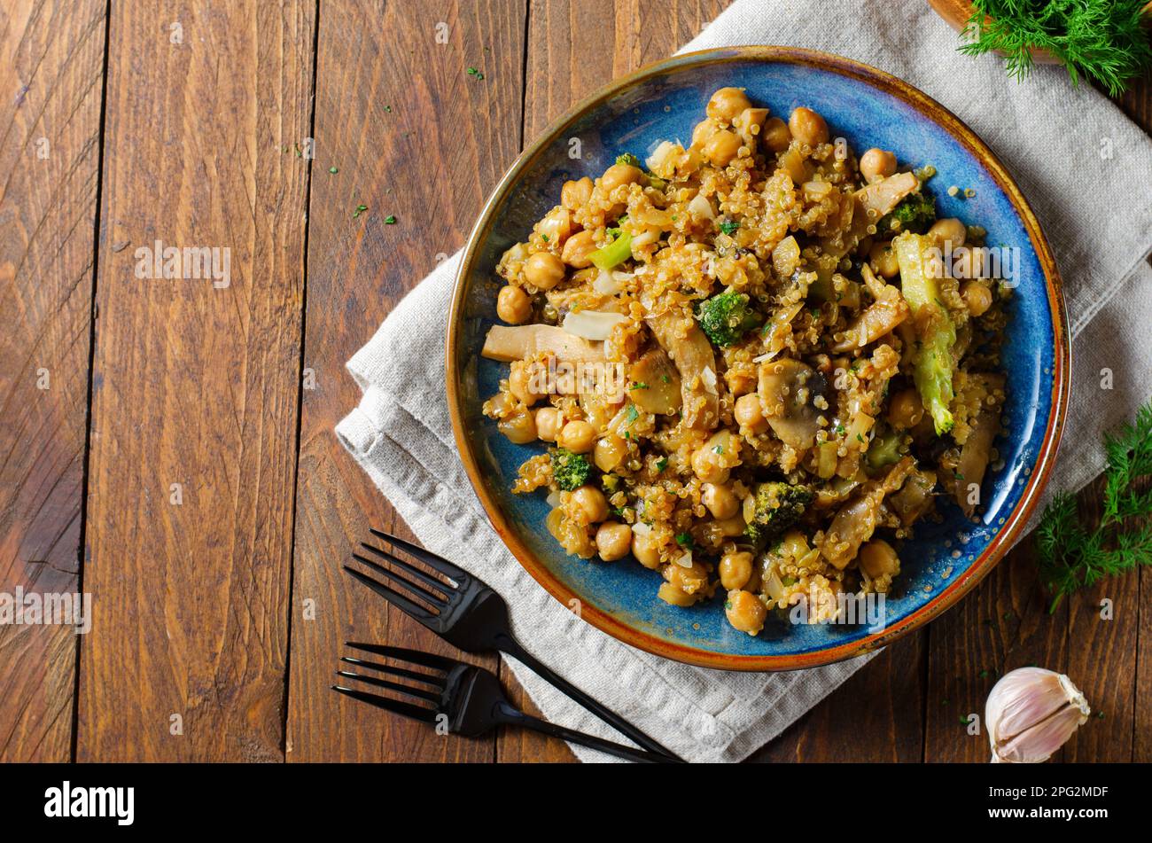 Quinoa con ceci, funghi e broccoli, pasto sano, cibo vegetariano, Sfondo rustico scuro Foto Stock