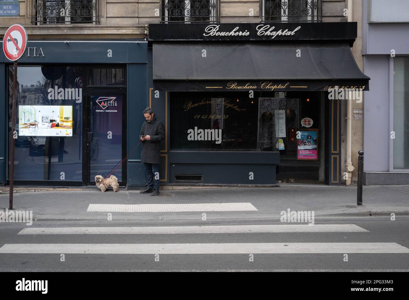 Uomo francese in attesa con un piccolo cane fuori macellaio a Montmartre, Parigi, Francia Foto Stock