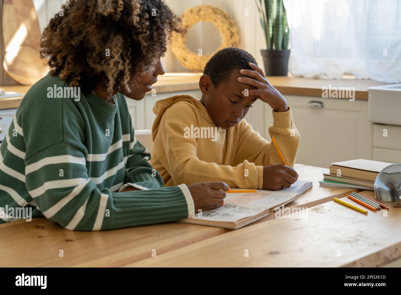 Caring African American mamma sostegno pensivo scolaro adottato figlio con l'incarico di istruzione a casa Foto Stock