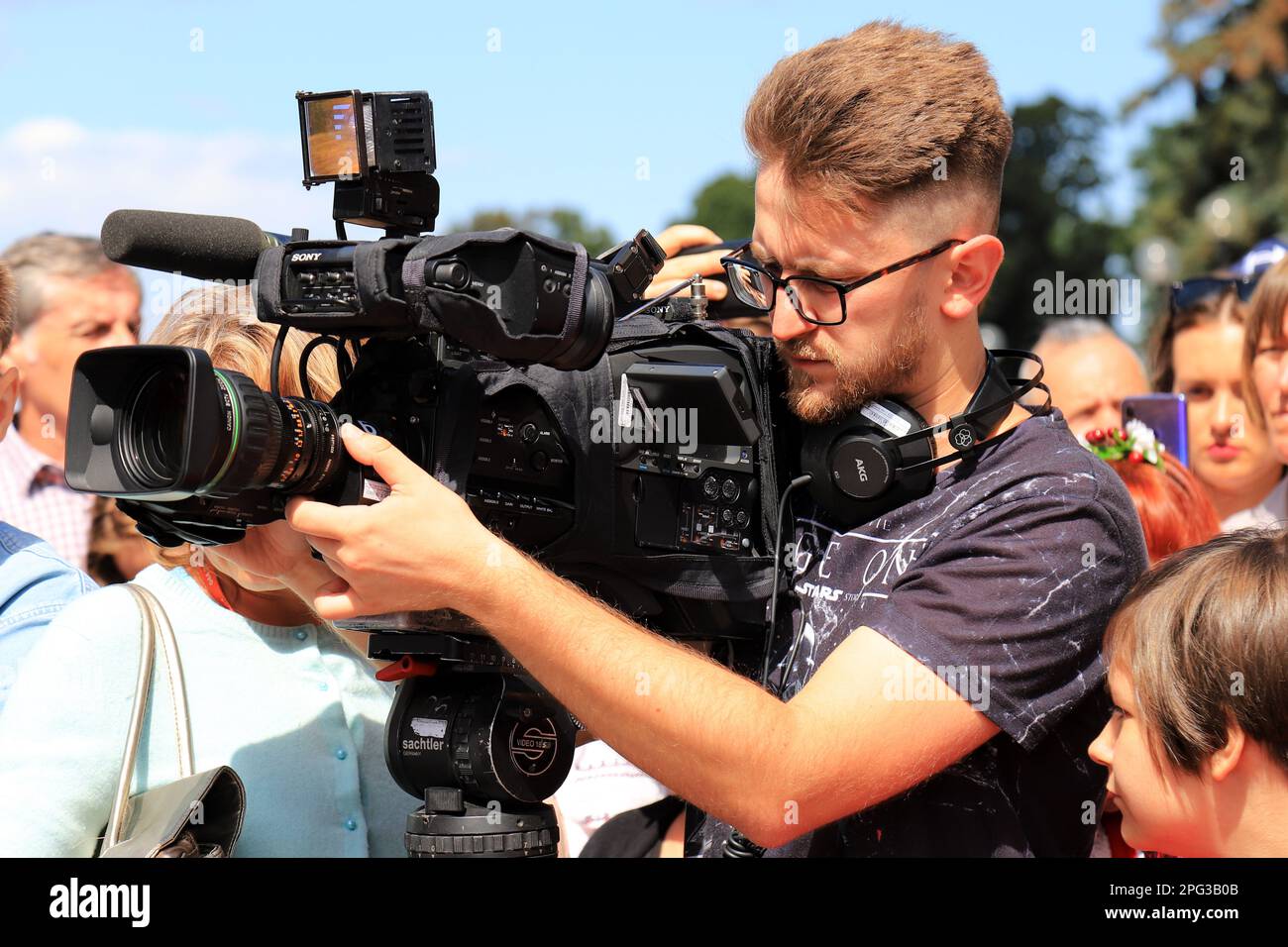 Operatore con telecamera professionale spara video a rally, protesta, evento. Giornalista corrispondente intervista, trasmissione in diretta per TV ch Foto Stock