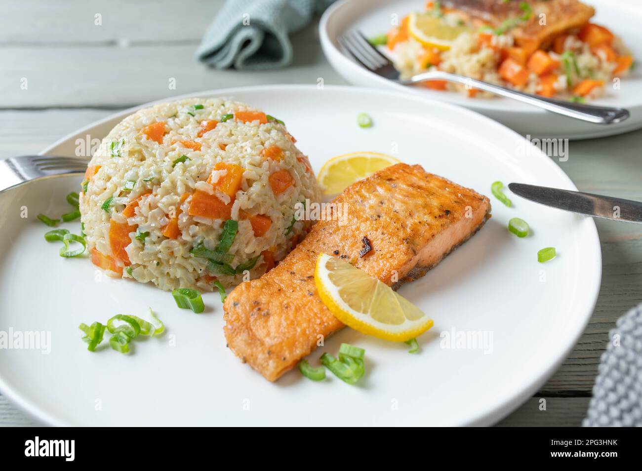 Salmone fritto con riso integrale, piselli, carote e porro su un piatto Foto Stock