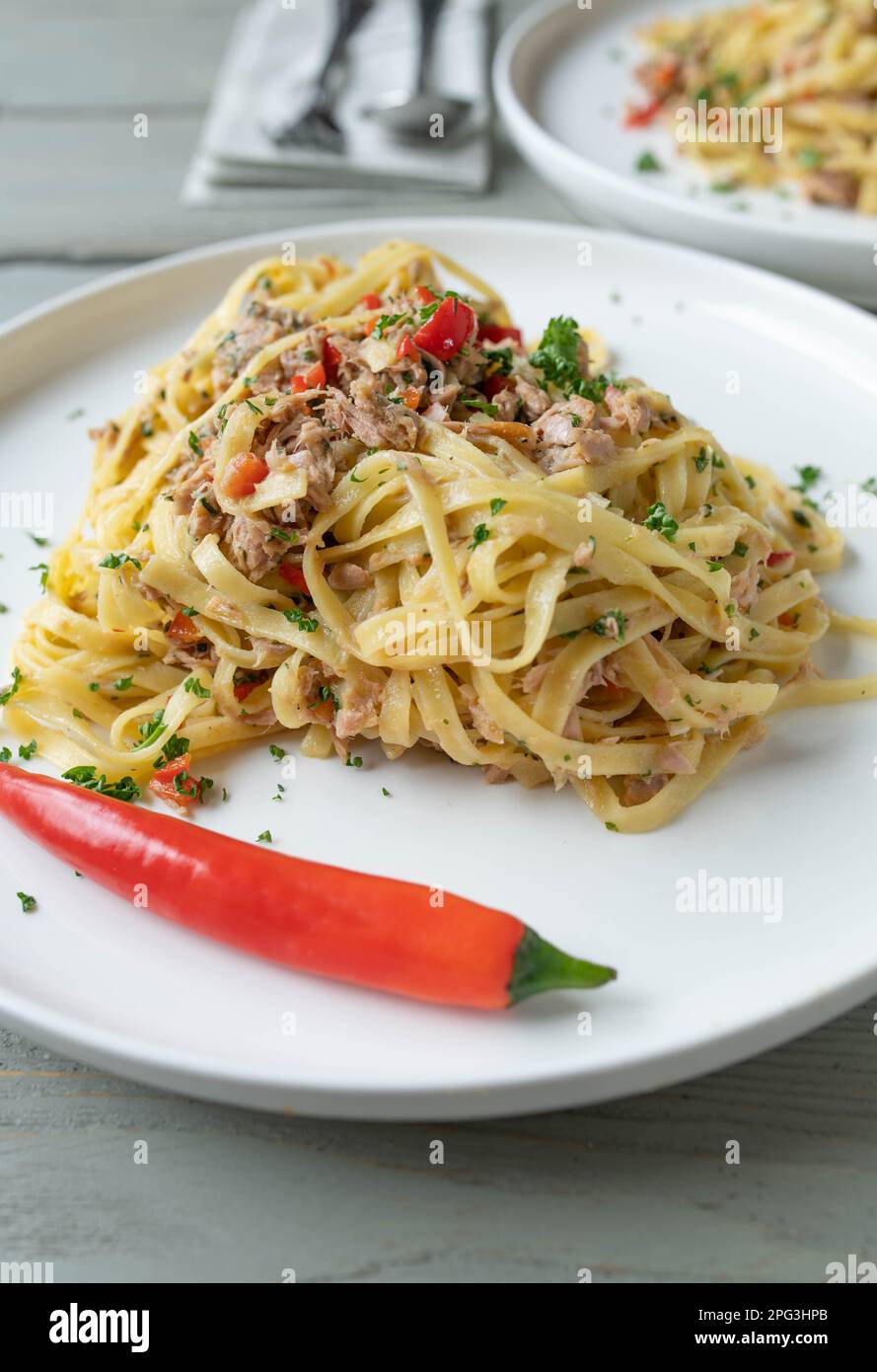Pasta con tonno, aglio, peperoncino, olio d'oliva e prezzemolo. Cucina tradizionale italiana Noodles aglio e olio su piatto Foto Stock