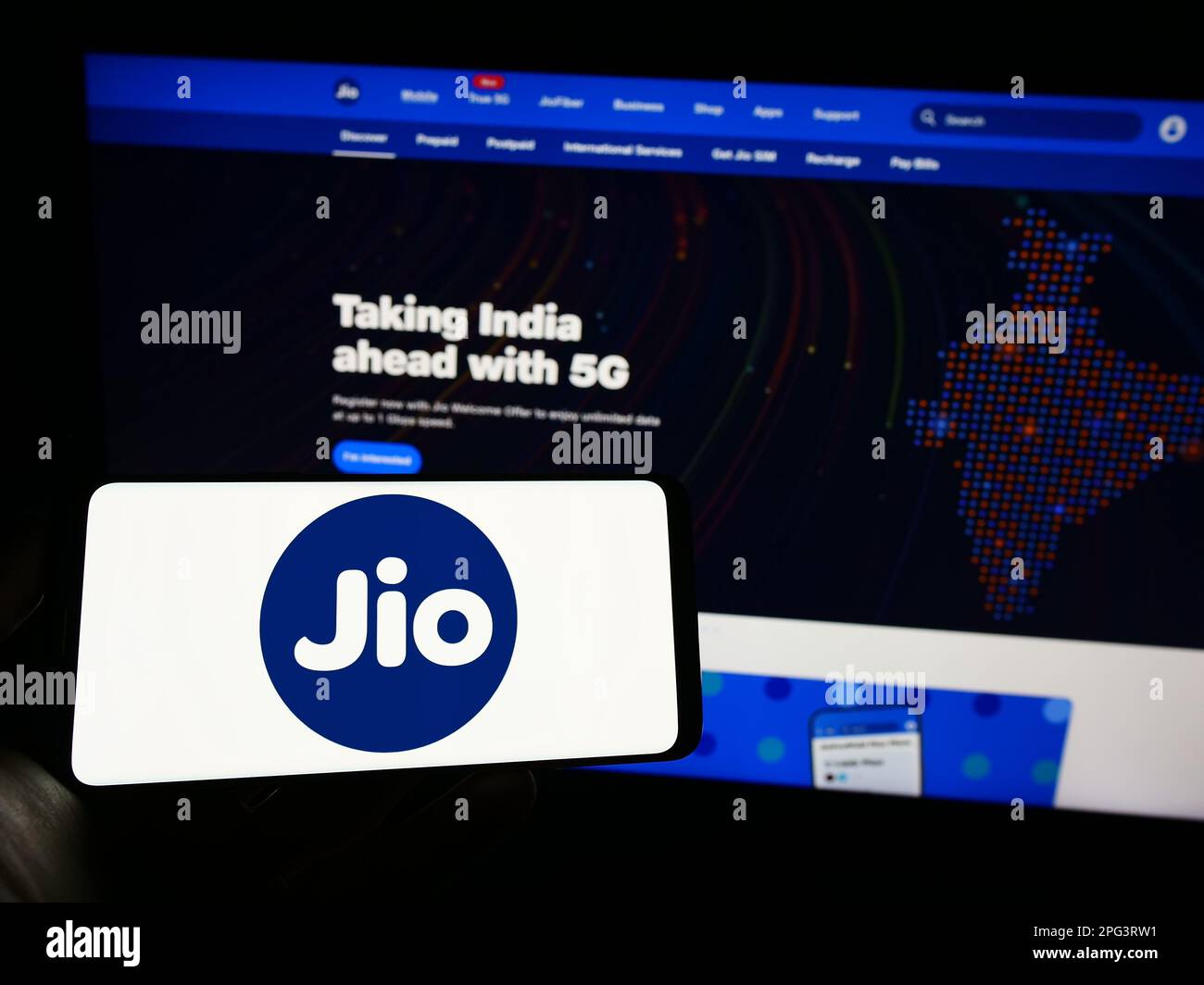 Persona che tiene il telefono cellulare con il logo della società indiana di telecomunicazioni Reliance Jio sullo schermo di fronte alla pagina web. Messa a fuoco sul display del telefono. Foto Stock