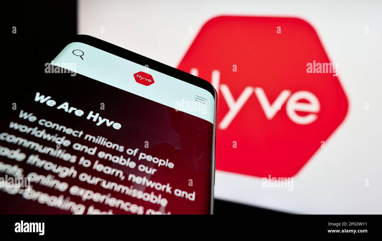 Telefono cellulare con sito web della società britannica di gestione eventi Hyve Group plc sullo schermo di fronte al logo. Messa a fuoco in alto a sinistra del display del telefono. Foto Stock