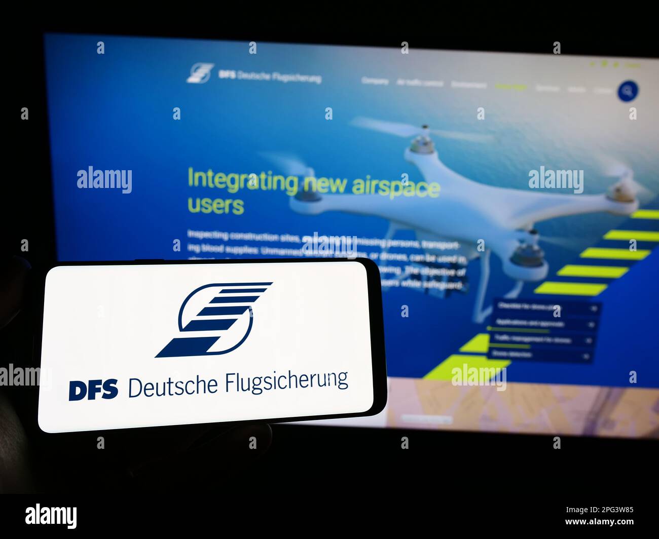 Persona che tiene in mano smartphone con il logo del controllo del traffico aereo DFS Deutsche Flugsicherung sullo schermo di fronte al sito web. Messa a fuoco sul display del telefono. Foto Stock
