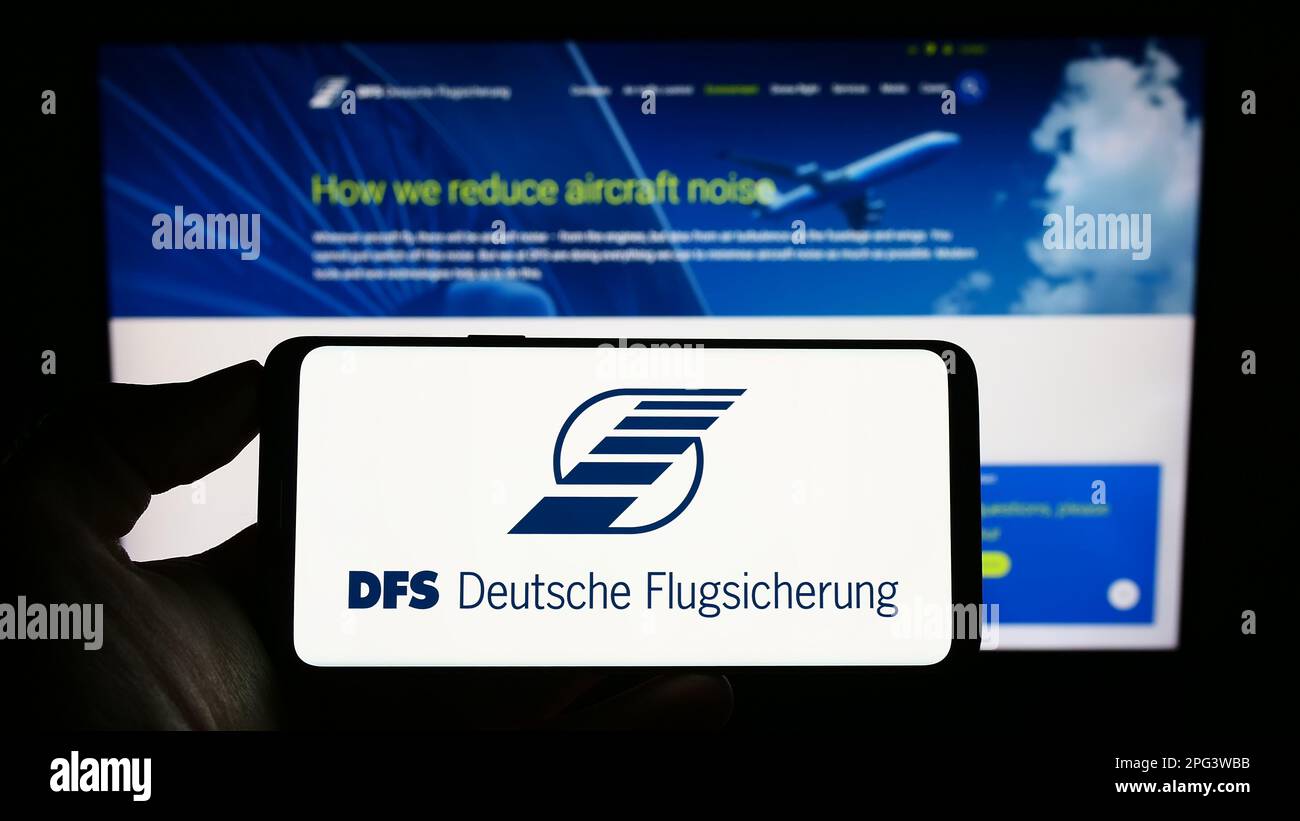 Persona che tiene il cellulare con il logo del controllo del traffico aereo DFS Deutsche Flugsicherung sullo schermo di fronte al sito web. Messa a fuoco sul display del telefono. Foto Stock
