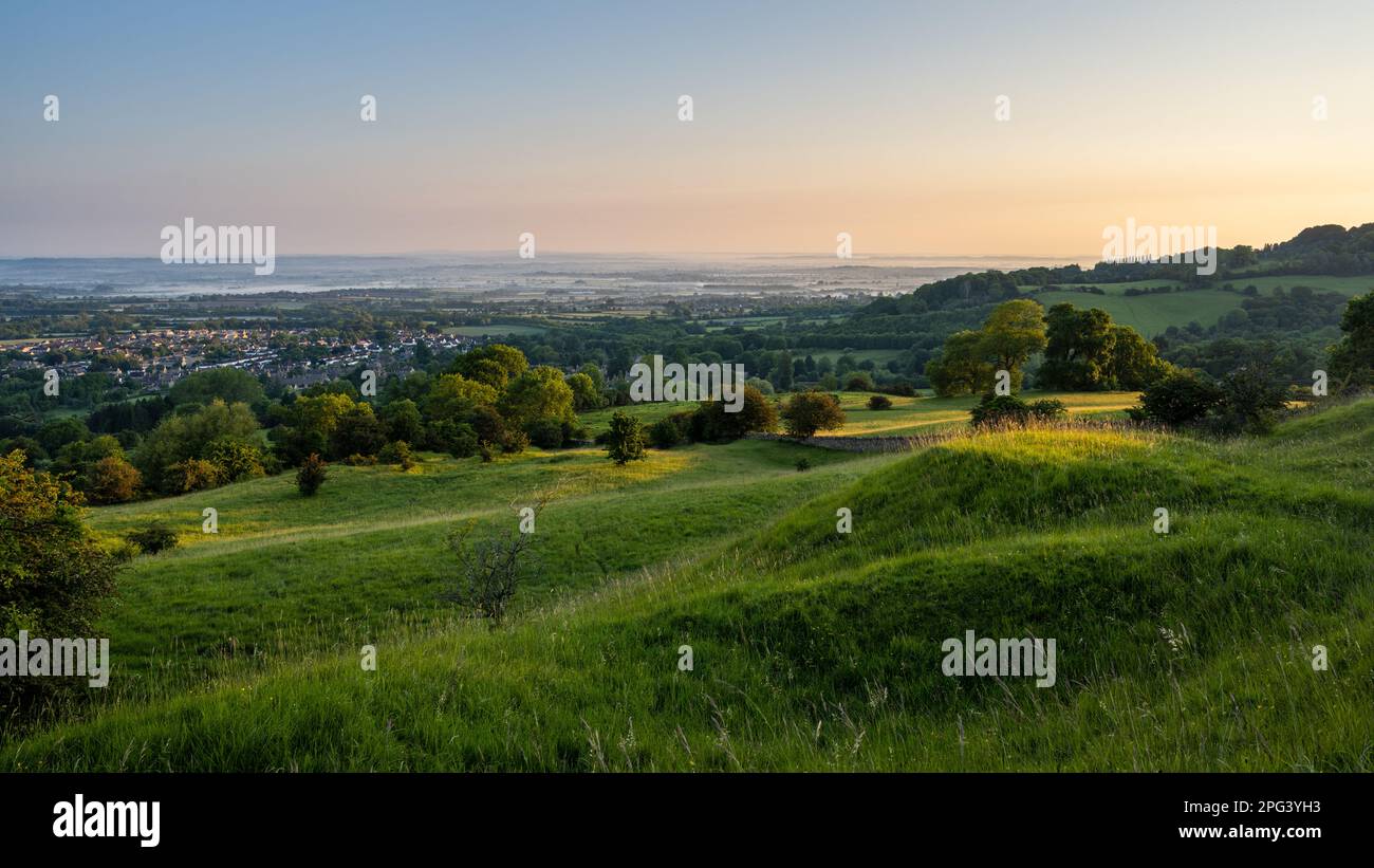 La luce dell'alba cade sul villaggio di Broadway e sul paesaggio misterico della vale of Evesham, come si vede da Broadway Hill sul Cotswold Edge nel Worcestershire. Foto Stock