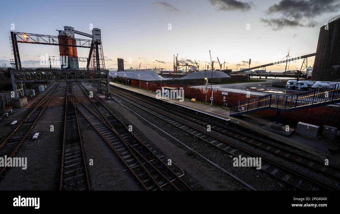 Il sole tramonta sui Docks di Avonmouth e sulla stazione di St Andrew's Road sulla ferrovia Severn Beach Line di Bristol. Foto Stock