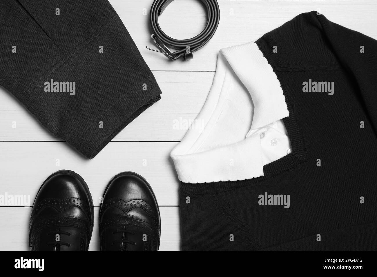 Uniforme da scuola elegante per ragazza su sfondo di legno bianco, piatto Foto Stock