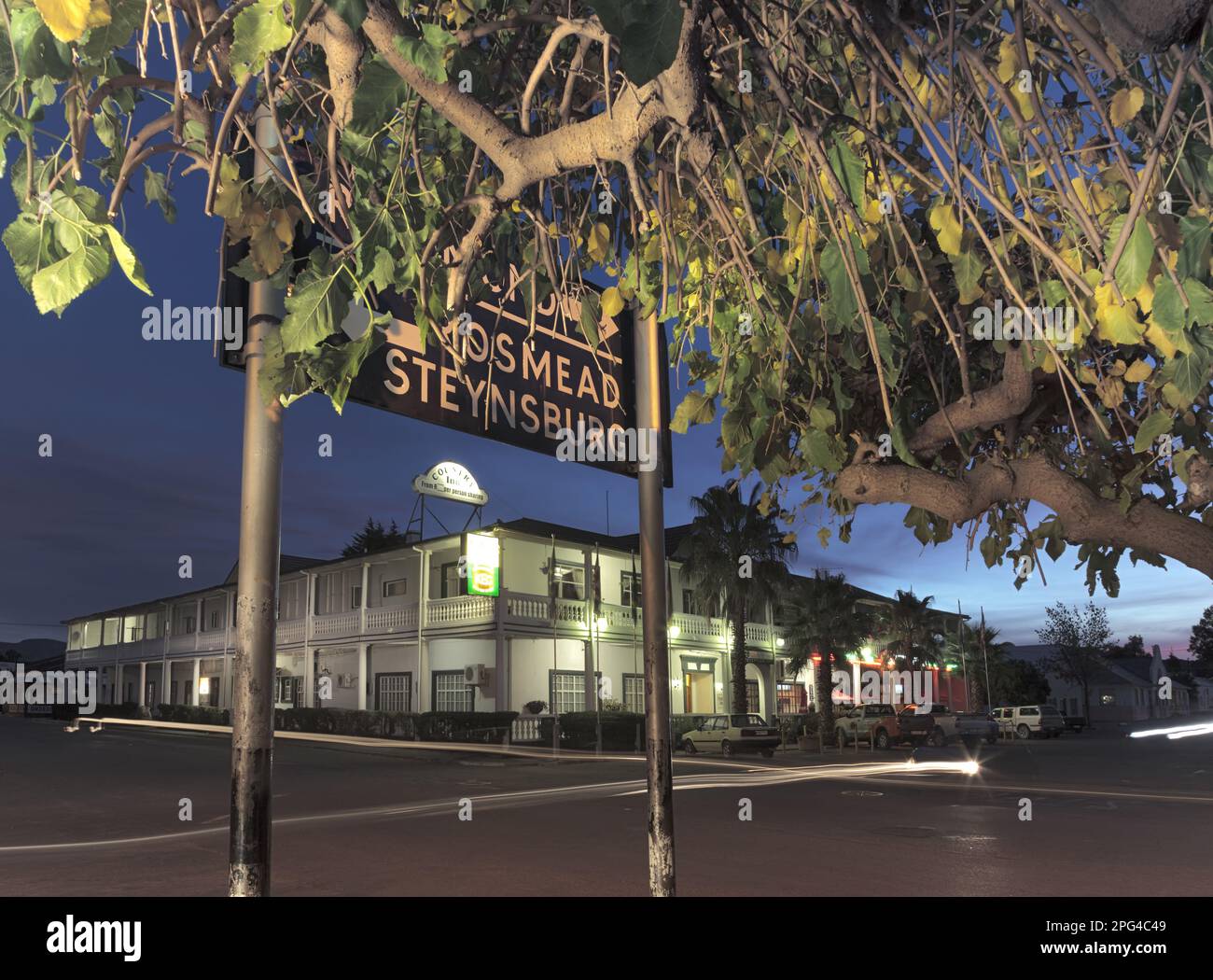 Al crepuscolo, i veicoli attraversano l'intersezione di Loop e Meintjies Street di fronte al Karoo Country Inn, lo storico hotel a tre stelle di Middelburg. Foto Stock