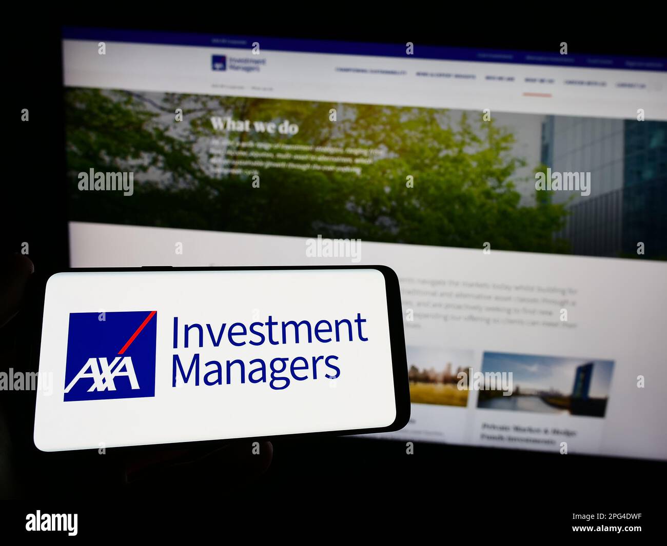 Persona che tiene uno smartphone con il logo della società di investimento Axa Investment Managers sullo schermo di fronte al sito Web. Messa a fuoco sul display del telefono. Foto Stock