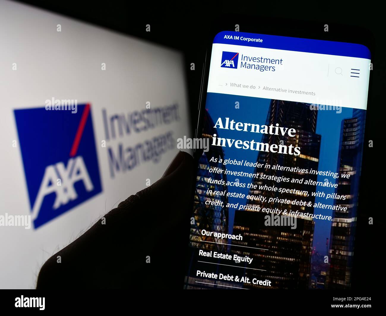 Persona che tiene il cellulare con il Web page della società di investimento Axa Investment Managers sullo schermo di fronte al logo. Messa a fuoco al centro del display del telefono. Foto Stock
