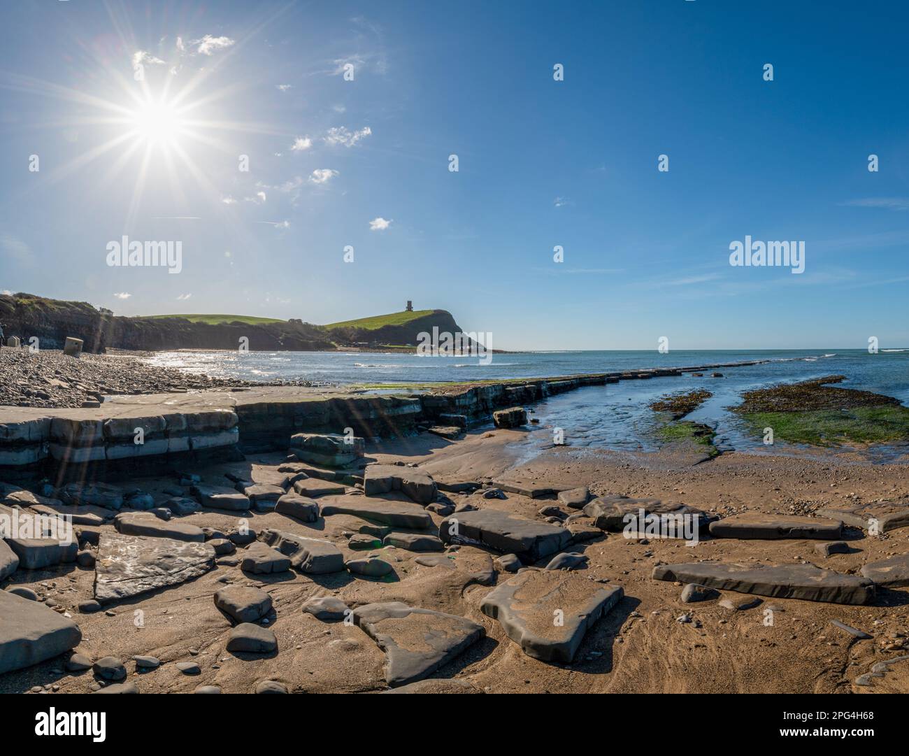La baia di Kimmeridge si presenta con la formazione di Clavell e sabbia di bronzo con alghe che escono in mare, la torre Clavell in lontananza sulla costa giurassica Foto Stock