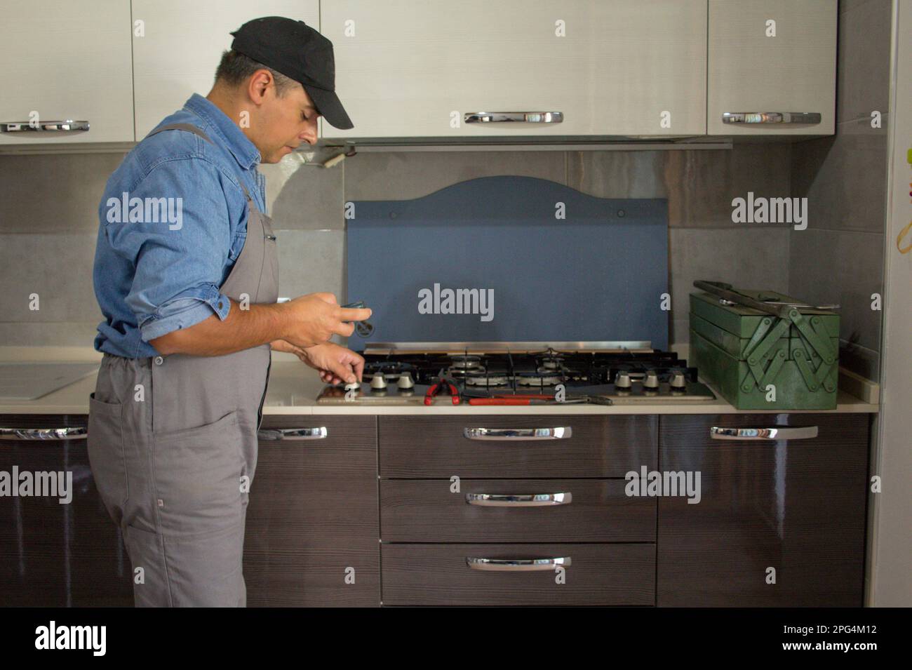 Immagine di un tecnico di handyman che con un rilevatore effettua controlli in cucina per la sicurezza e le perdite di gas dalla stufa. Prevenzione e sicurezza Foto Stock