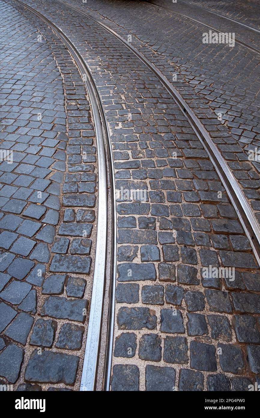 Dettaglio del pavimento in ciottoli di una strada a lisbona con le tracce del tram che descrivono una curva nel quartiere Alfama, verticale Foto Stock