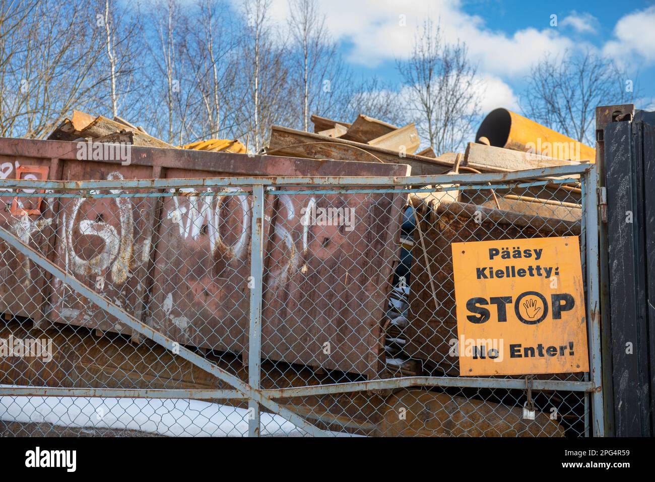 Pääsy kielletty: FERMATA. Nessun invio! Segno giallo su una recinzione, rottami metallici su un contenitore sullo sfondo nel distretto di Kyläsaari, Helsinki, Finlandia. Foto Stock