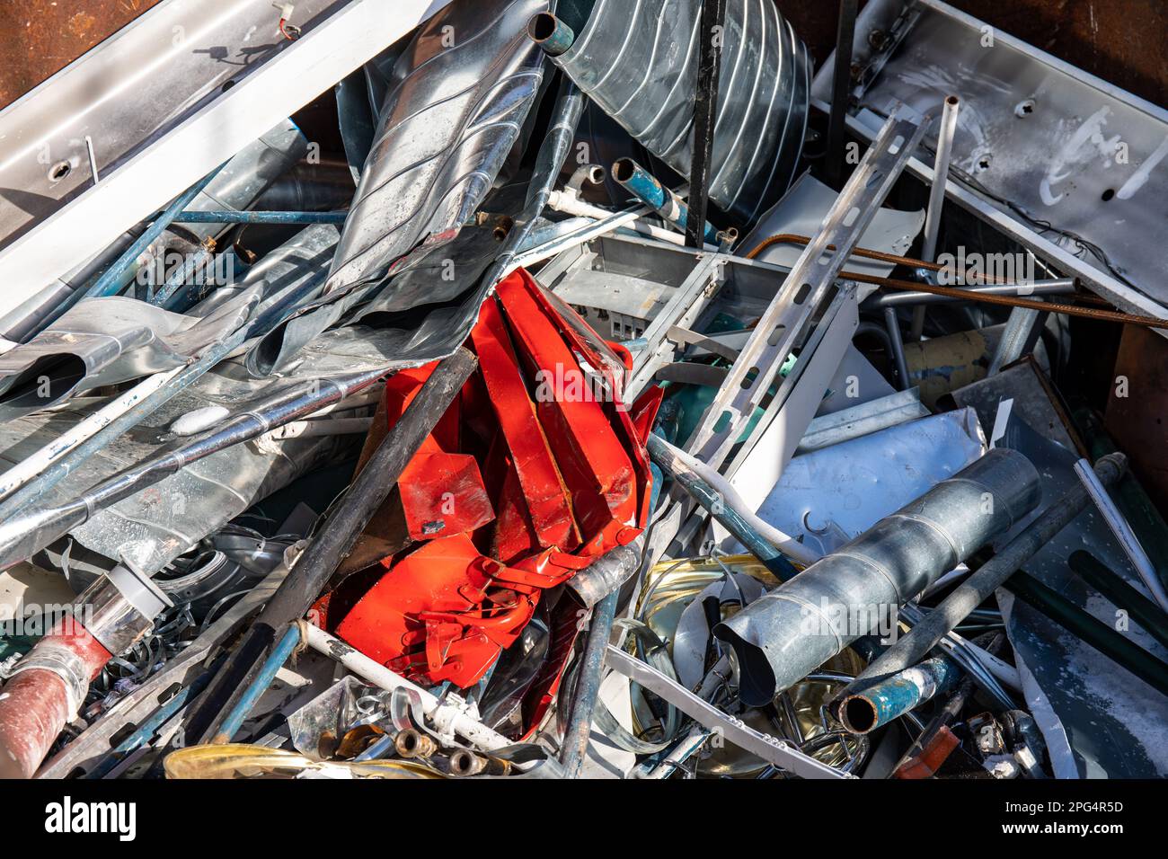 Pezzo rosso di metallo in un contenitore di metallo di scarto Foto Stock