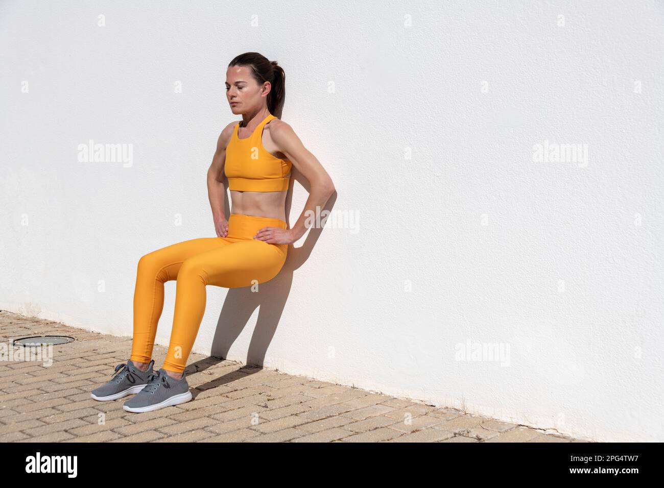 Adatta la donna che fa esercizio squat contro un muro Foto Stock