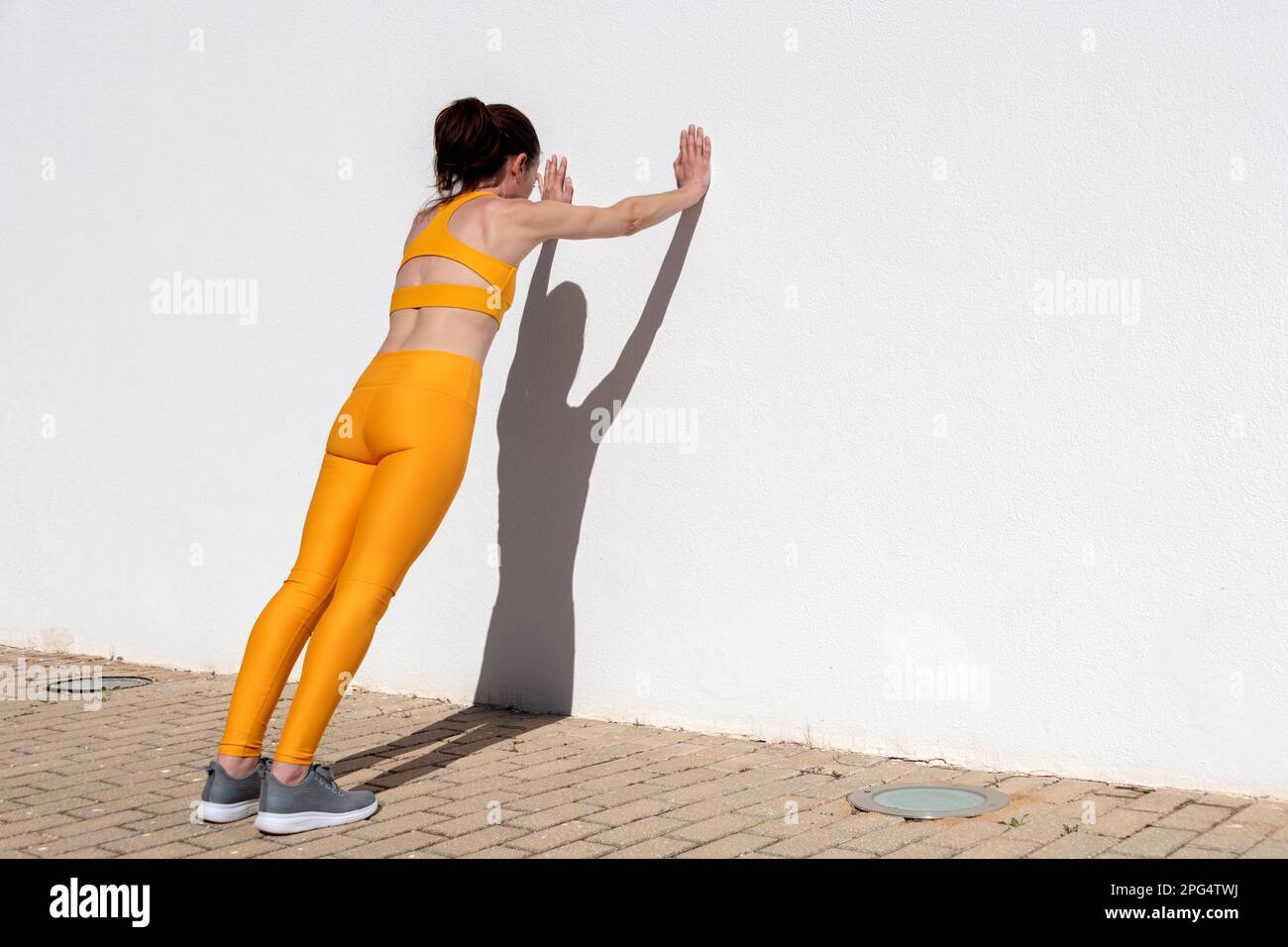 Donna sportiva che fa esercizi di spinta contro una parete Foto Stock