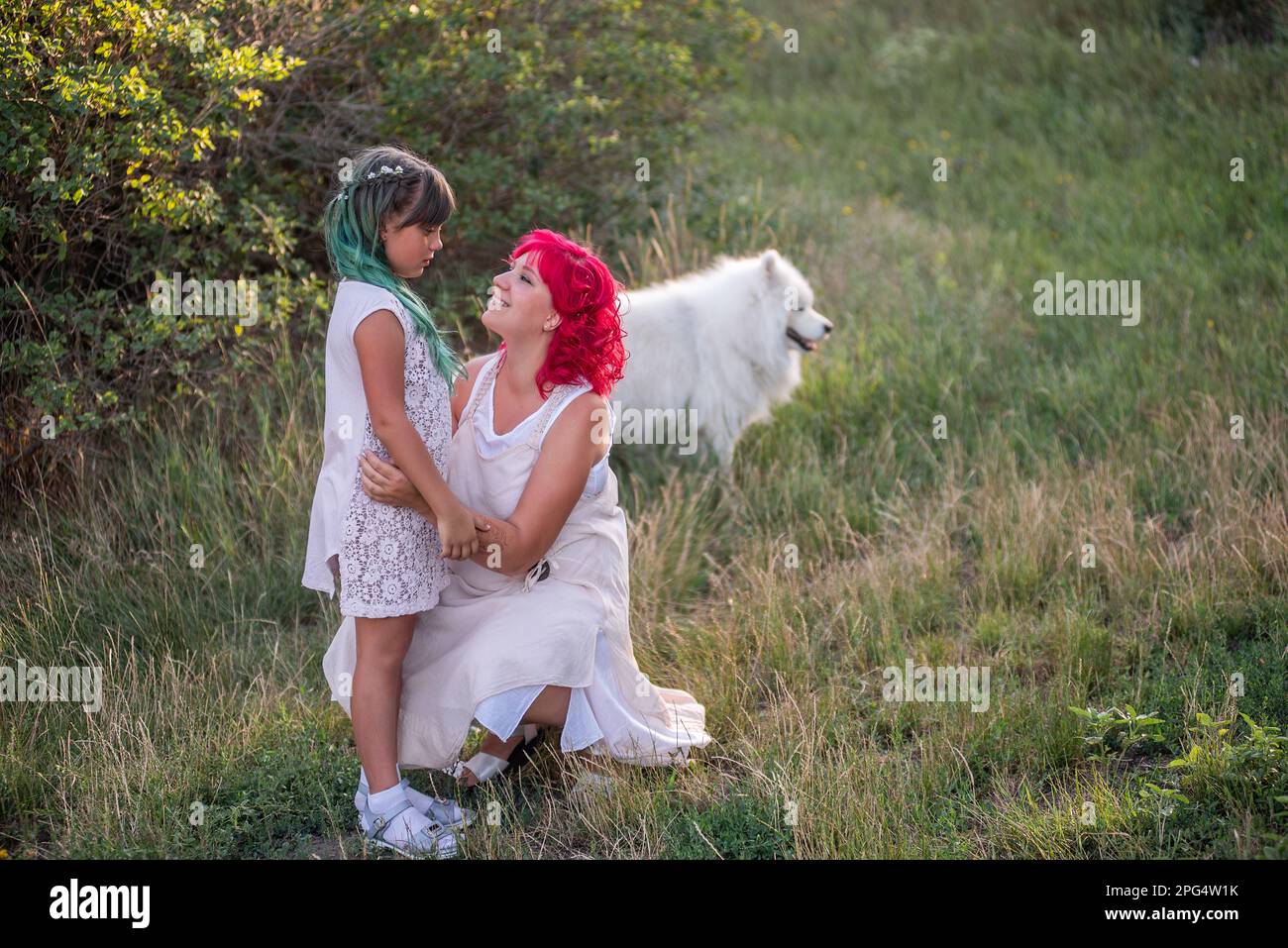 Luminosa, diversità, straordinaria madre e figlia che abbraccia la foresta. La donna ha i capelli rosa, la ragazza ha i capelli verdi. Tenera maternità, buon chi Foto Stock