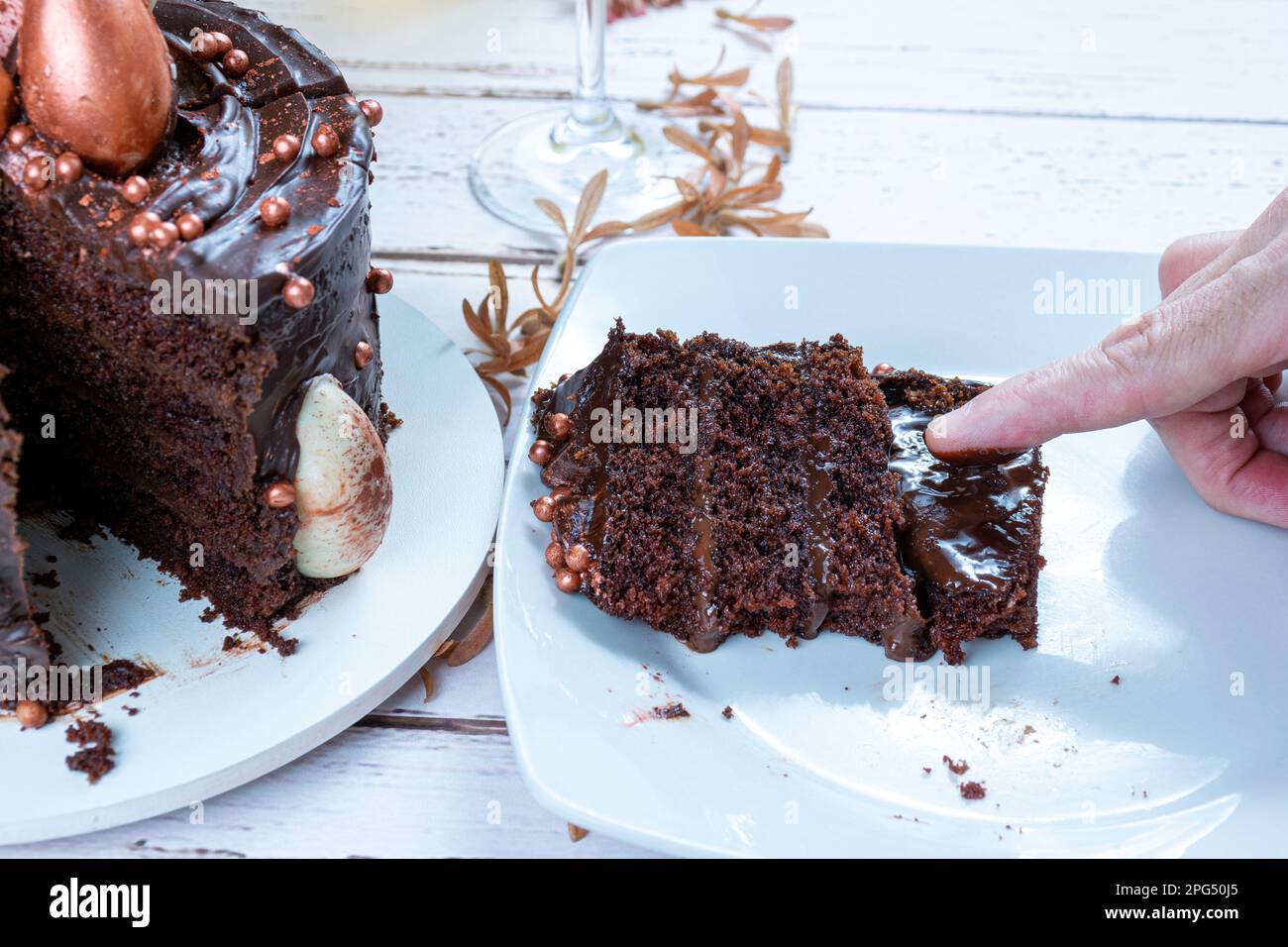Dito maschio che tocca il ripieno di ganache della torta al cioccolato fondente. Foto Stock