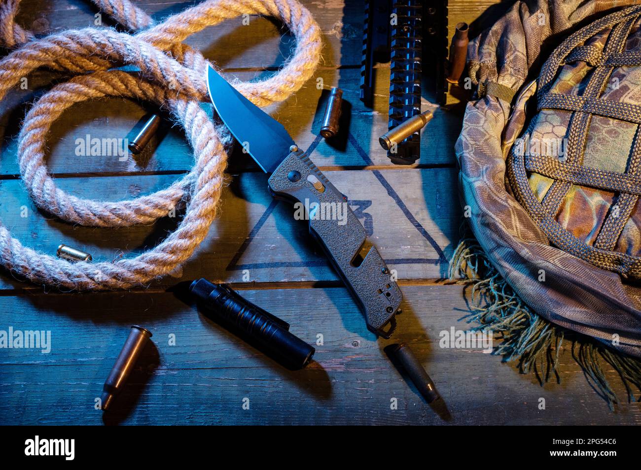 Composizione militare con coltello e corda. Corda e maniche su una scatola militare. Luce gialla calda. Tasca per coltello e torcia. Vista dall'alto. Foto Stock