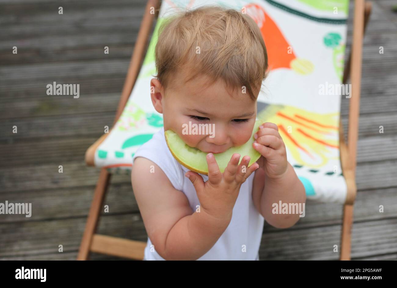 Il bambino che mangia un melone della melone della melata del miele Foto Stock