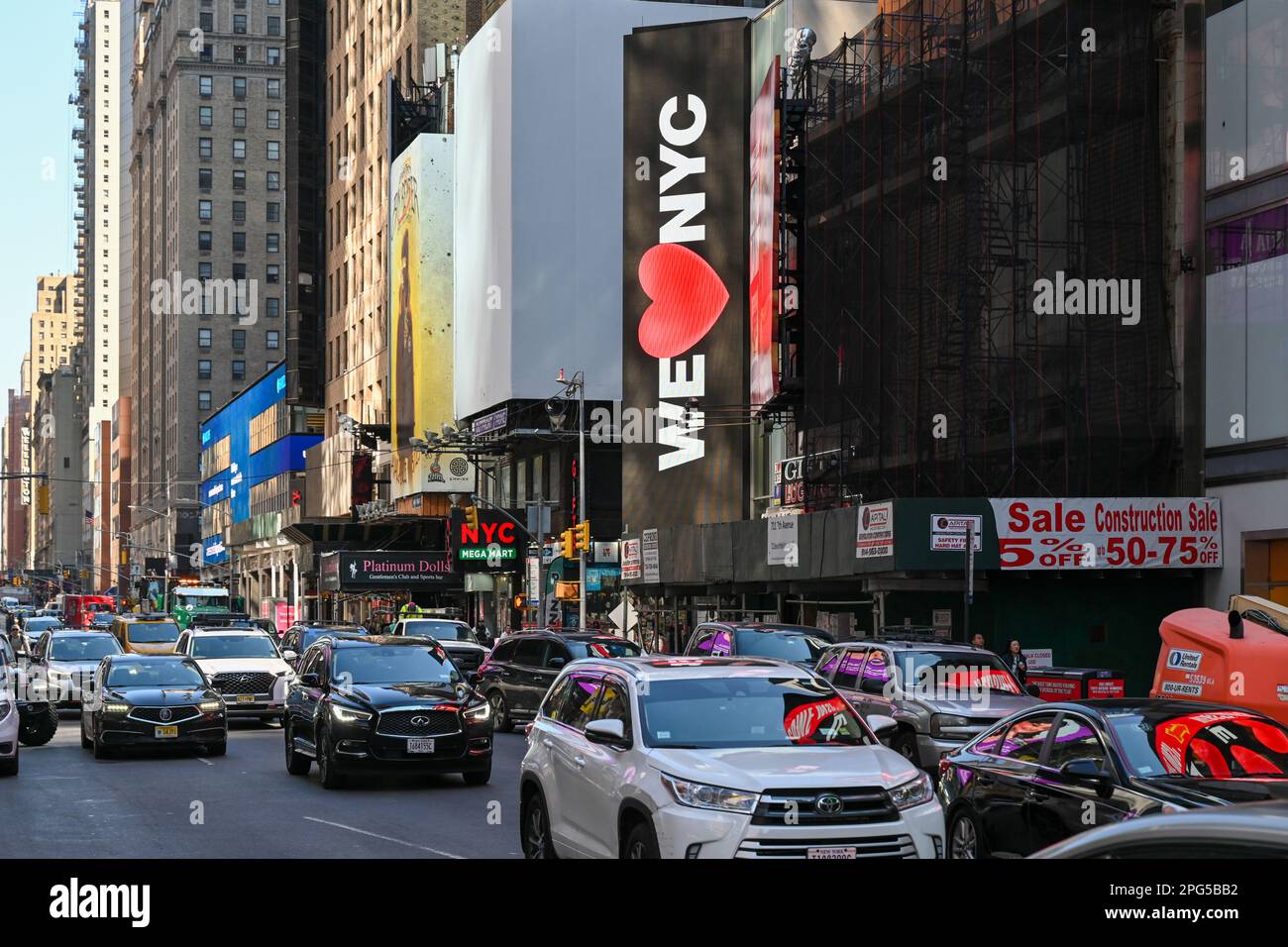 Le persone camminano vicino a cartelloni digitali che mostrano 'We Love NYC' durante l'evento di lancio della campagna per 'We Love NYC' a Times Square il 20 marzo 2023 in N Foto Stock