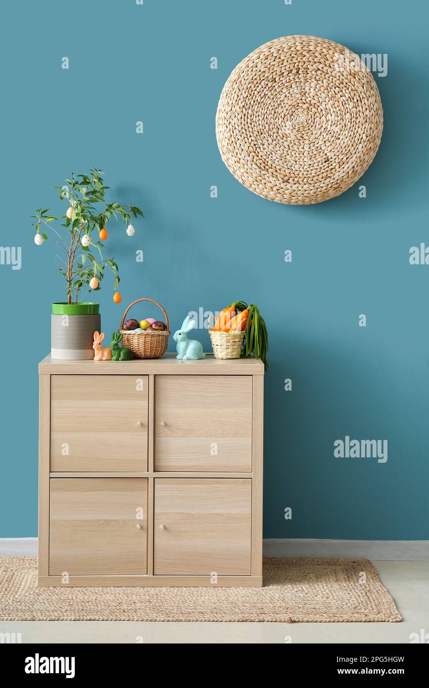 Decorazioni pasquali su armadio in legno vicino alle pareti blu Foto Stock
