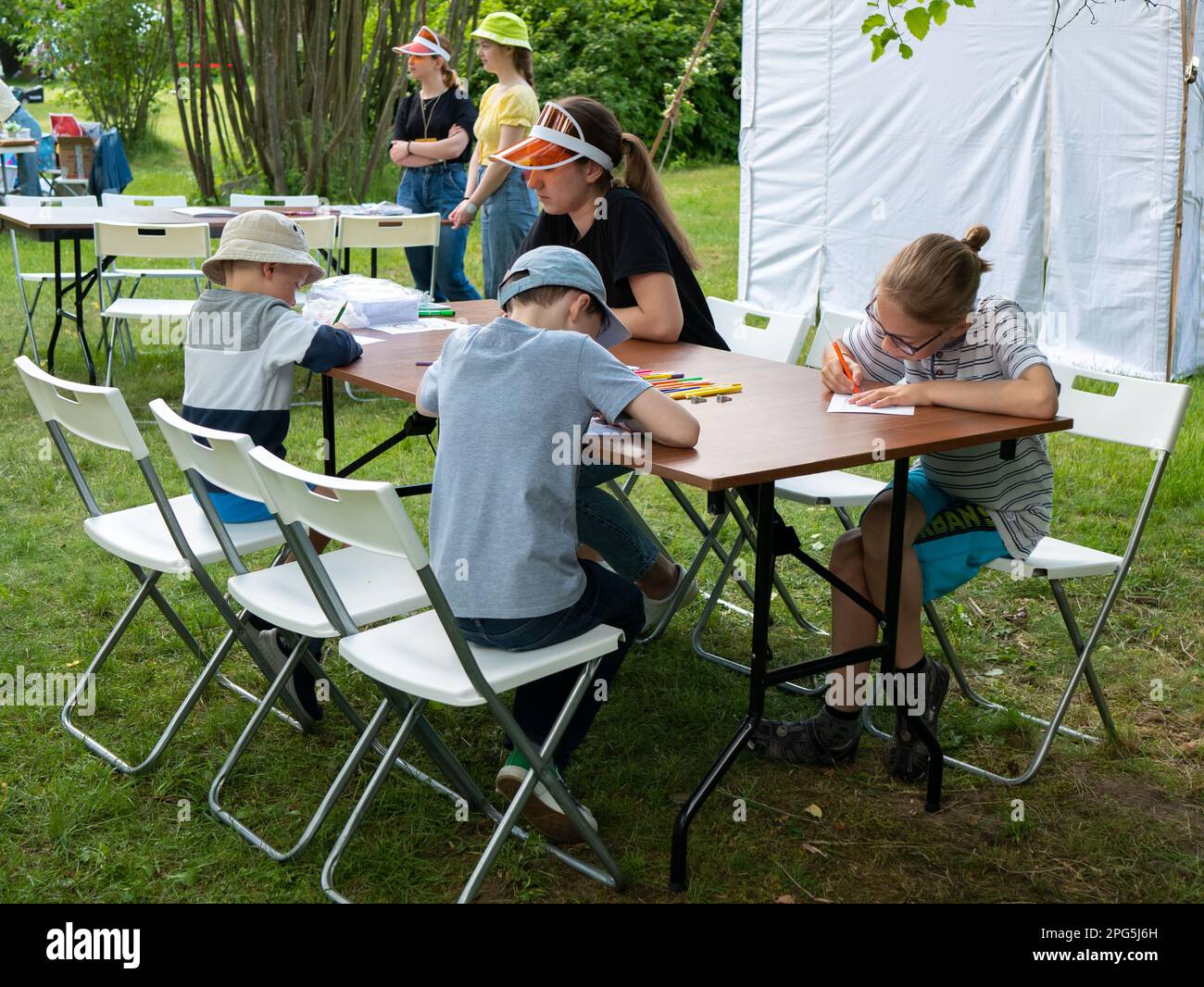 Minsk, Bielorussia - 12 giugno 2022: I bambini stanno disegnando al grande tavolo all'esterno in natura, fuoco selettivo. Attività ricreative estive. Campo estivo Foto Stock
