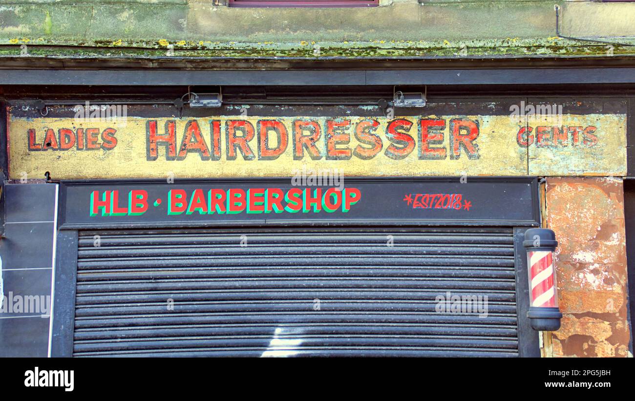 vecchio cartello del barbiere stagionato sull'edificio in pietra arenaria rossa Foto Stock