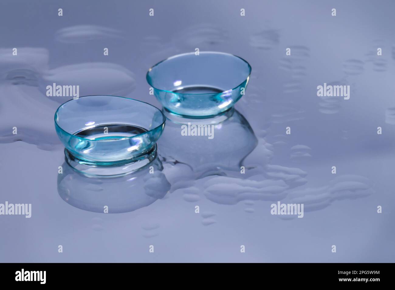 Lenti a contatto e gocce d'acqua sulla superficie riflettente la luce. Spazio per il testo Foto Stock