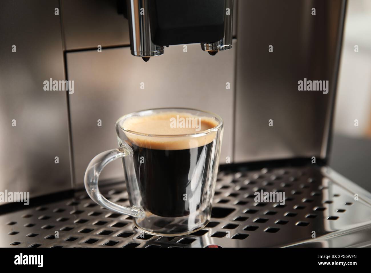 Macchina espresso con tazza di caffè fresco su vassoio antigoccia, primo piano Foto Stock