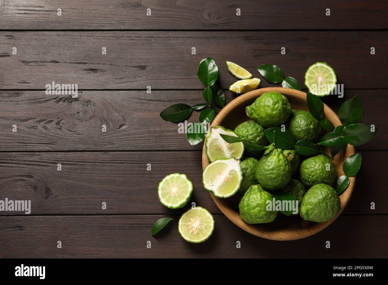 Frutti di bergamotto maturi interi e tagliati con foglie verdi su tavola di legno, giacitura piatta. Spazio per il testo Foto Stock