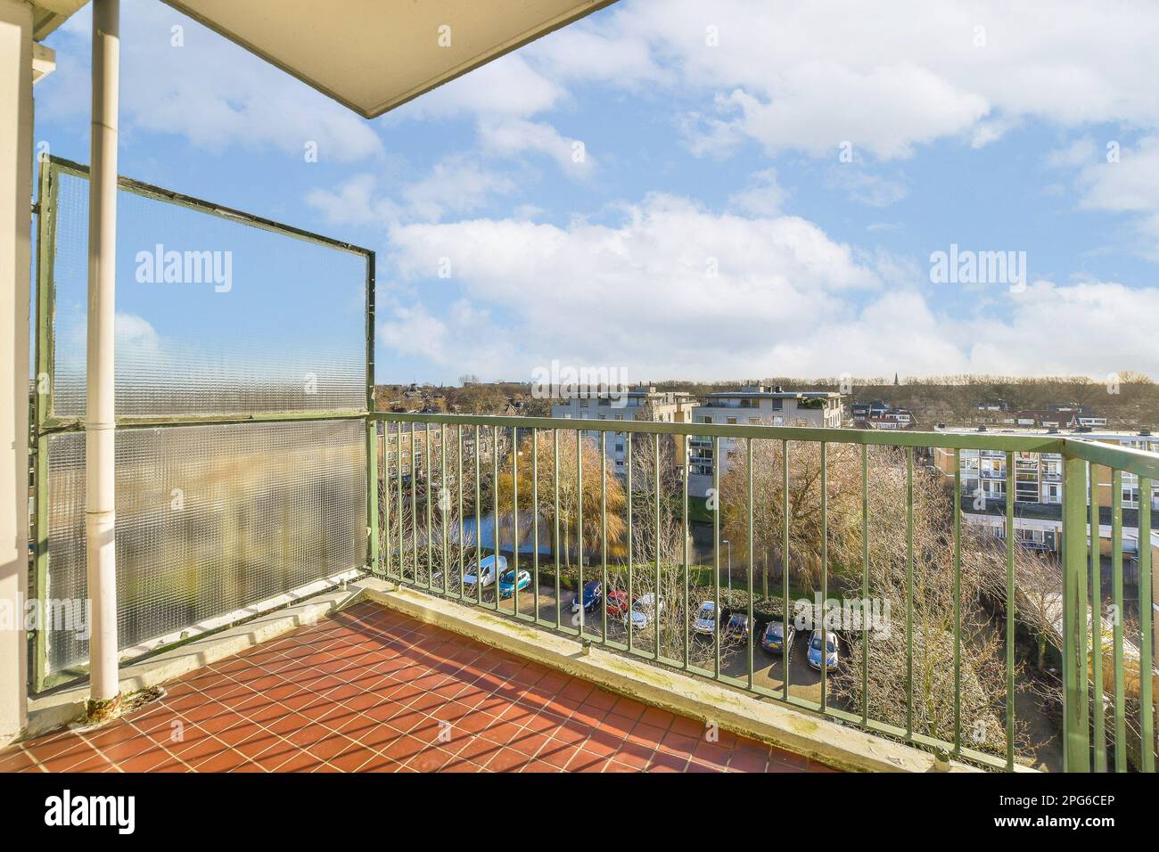 un balcone con piastrelle rosse sul pavimento e nuvole bianche nella vista cielo blu si trova da dietro di esso Foto Stock