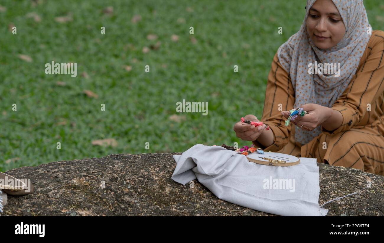 Donne che si preparano al lavoro progetto di ricamo con tessuto, fili e cerchio all'aperto. Foto Stock