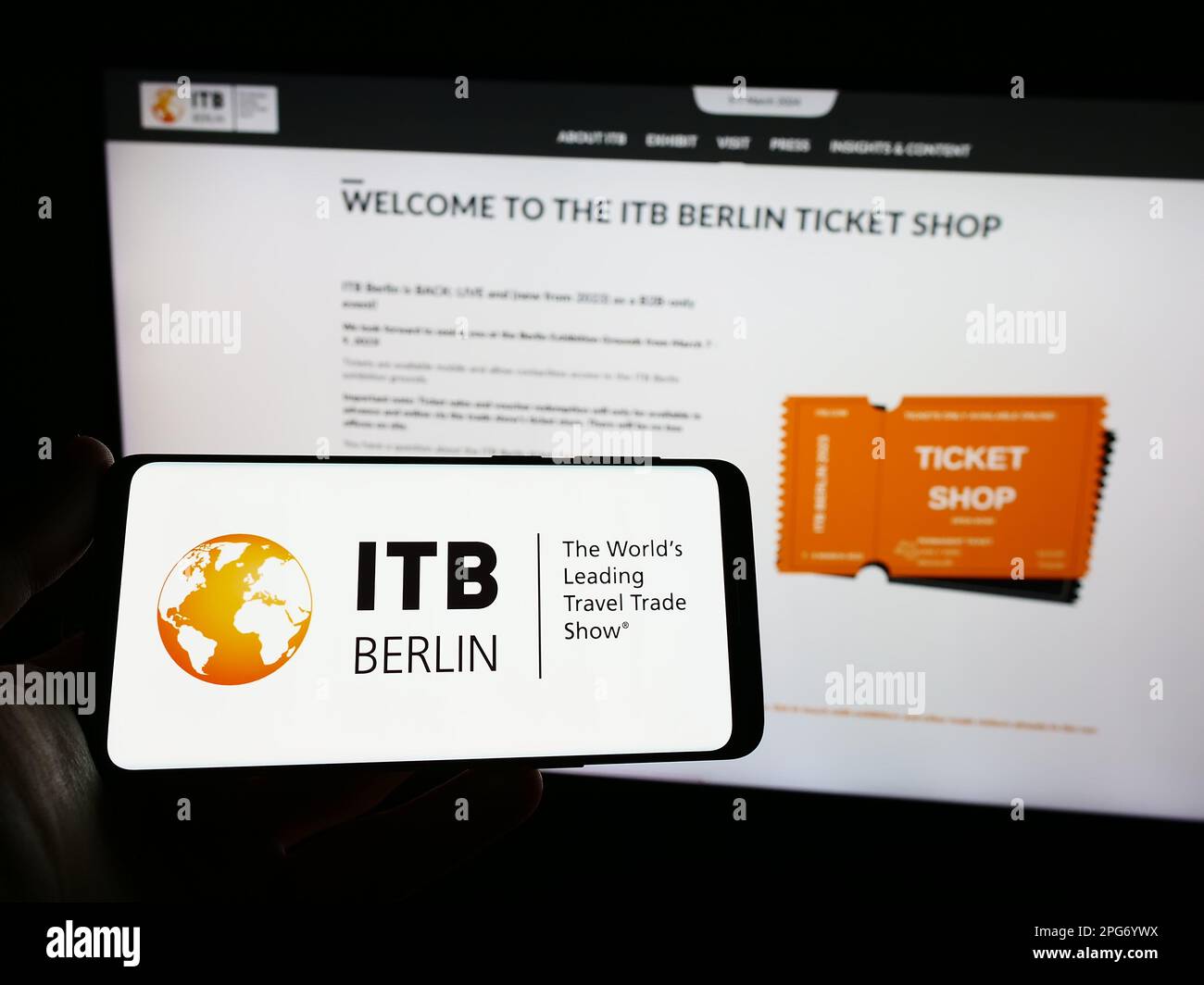 Persona che tiene uno smartphone con il logo della fiera turistica tedesca ITB Berlin sullo schermo di fronte al sito web. Messa a fuoco sul display del telefono. Foto Stock