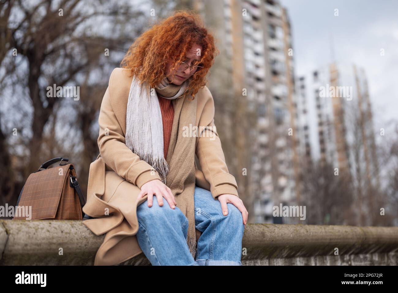 Ritratto naturale di una donna zenzero caucasica con lenticelle e capelli ricci. È depressa. Foto Stock