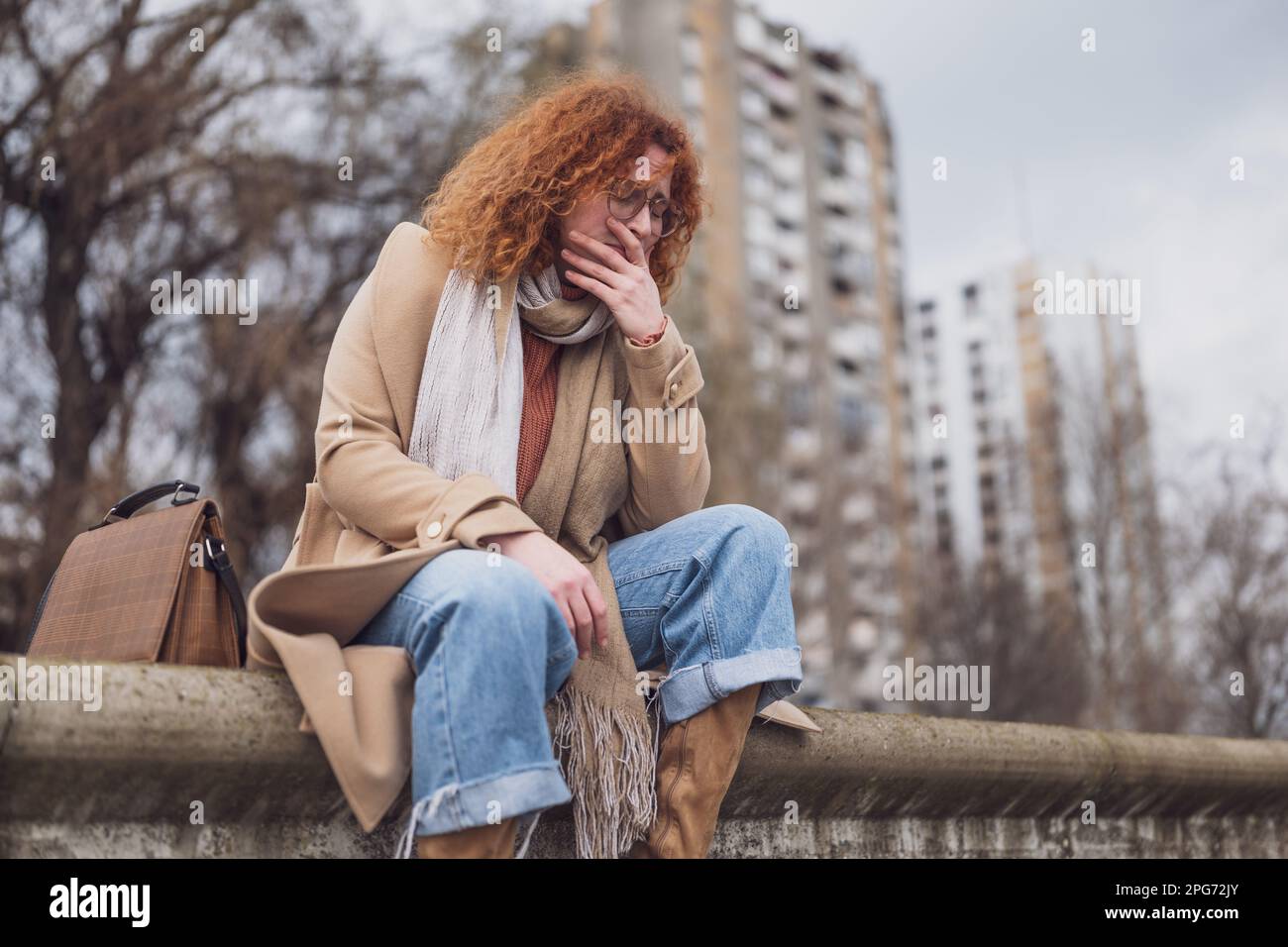 Ritratto naturale di una donna zenzero caucasica con lenticelle e capelli ricci. È depressa. Foto Stock