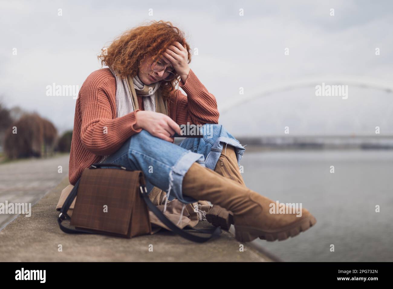 Ritratto naturale di una donna zenzero caucasica con lenticelle e capelli ricci. È stanca e depressa. Foto Stock