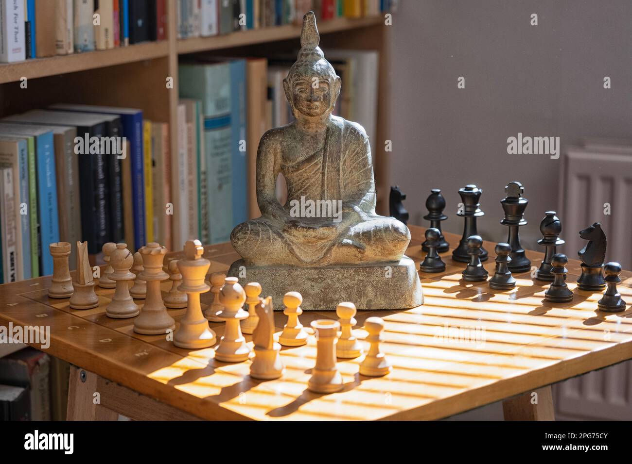 Scacchiera con statua di Buddha e raggi del sole Foto Stock