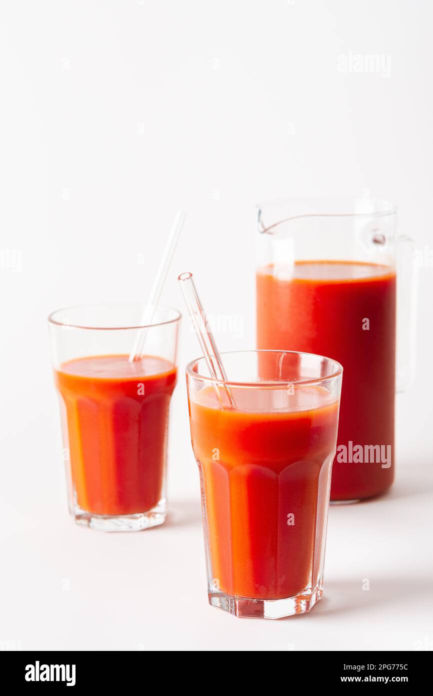 Succo di pomodoro appena spremuto in casa in bicchieri e una caraffa su sfondo bianco Foto Stock
