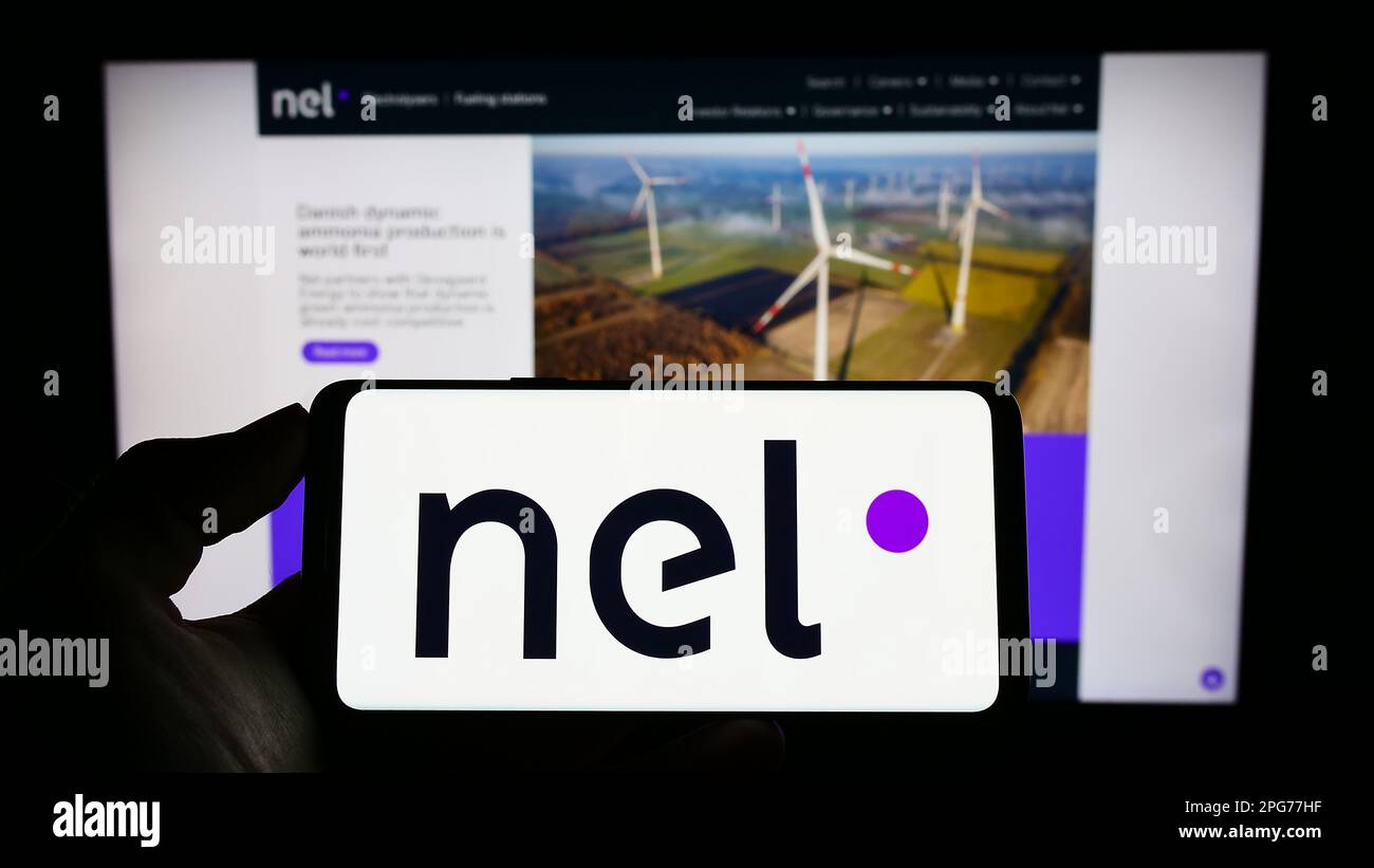 Persona che tiene il cellulare con il logo della società norvegese di idrogeno nel ASA sullo schermo di fronte alla pagina web aziendale. Messa a fuoco sul display del telefono. Foto Stock