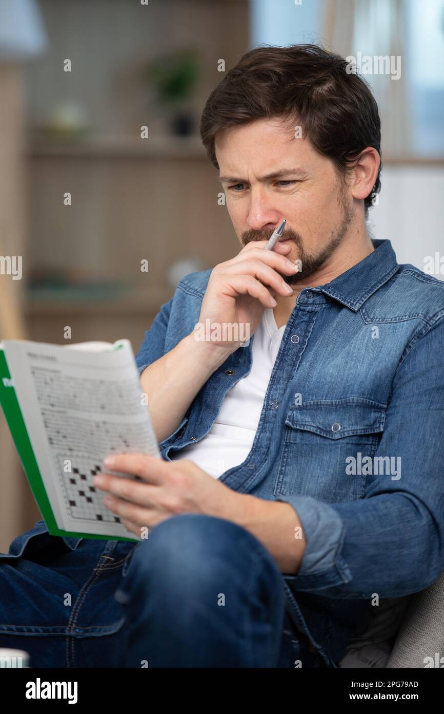 giovane uomo seduto facendo un puzzle crossword Foto Stock