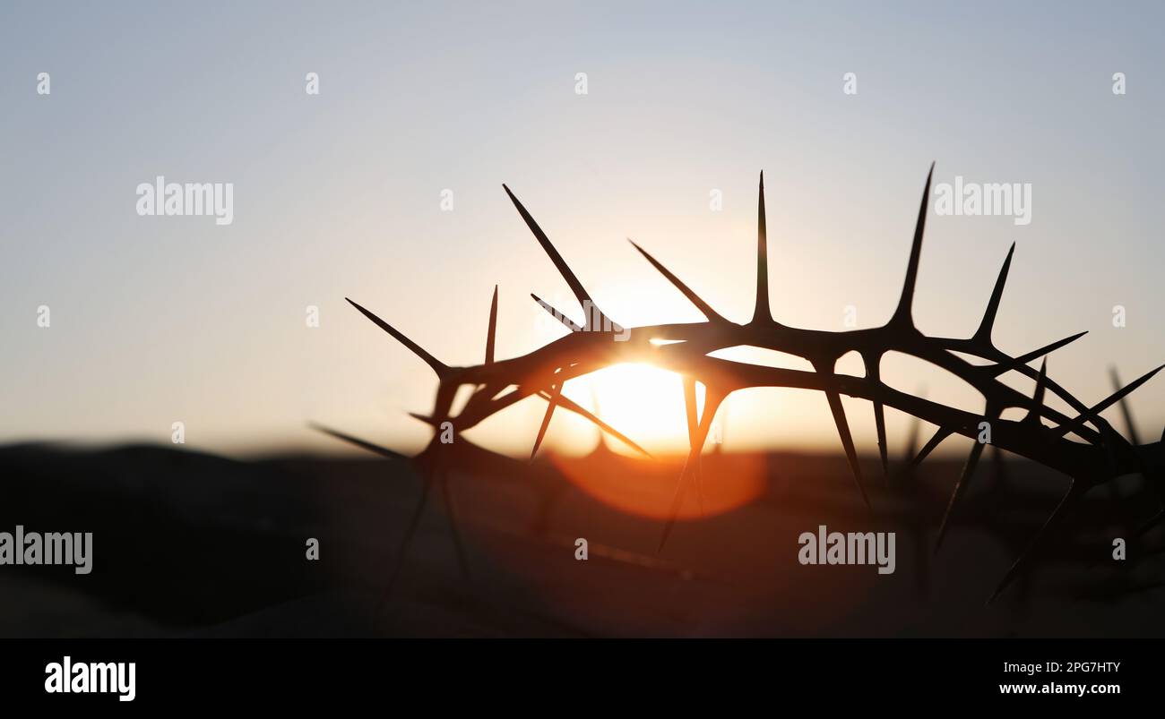 La croce e la corona delle spine che simboleggiano il sacrificio e la sofferenza di Gesù Cristo e il tramonto rosso, la settimana della Passione e il concetto di Quaresima Foto Stock