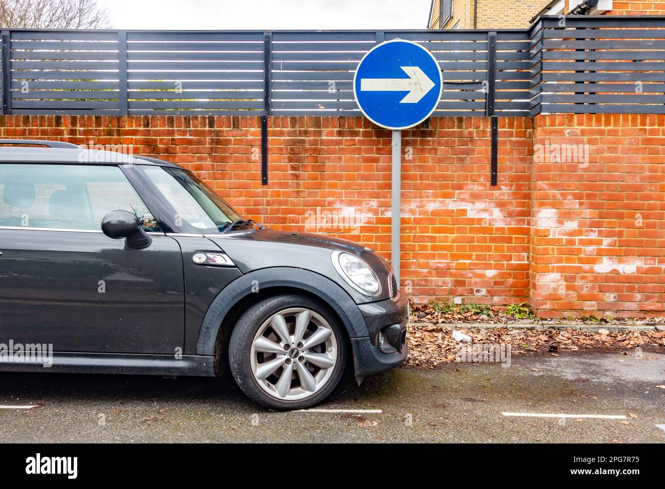 Una BMW mini parcheggiata di fronte a un cartello stradale che indica la direzione di viaggio lungo una strada a senso unico Foto Stock