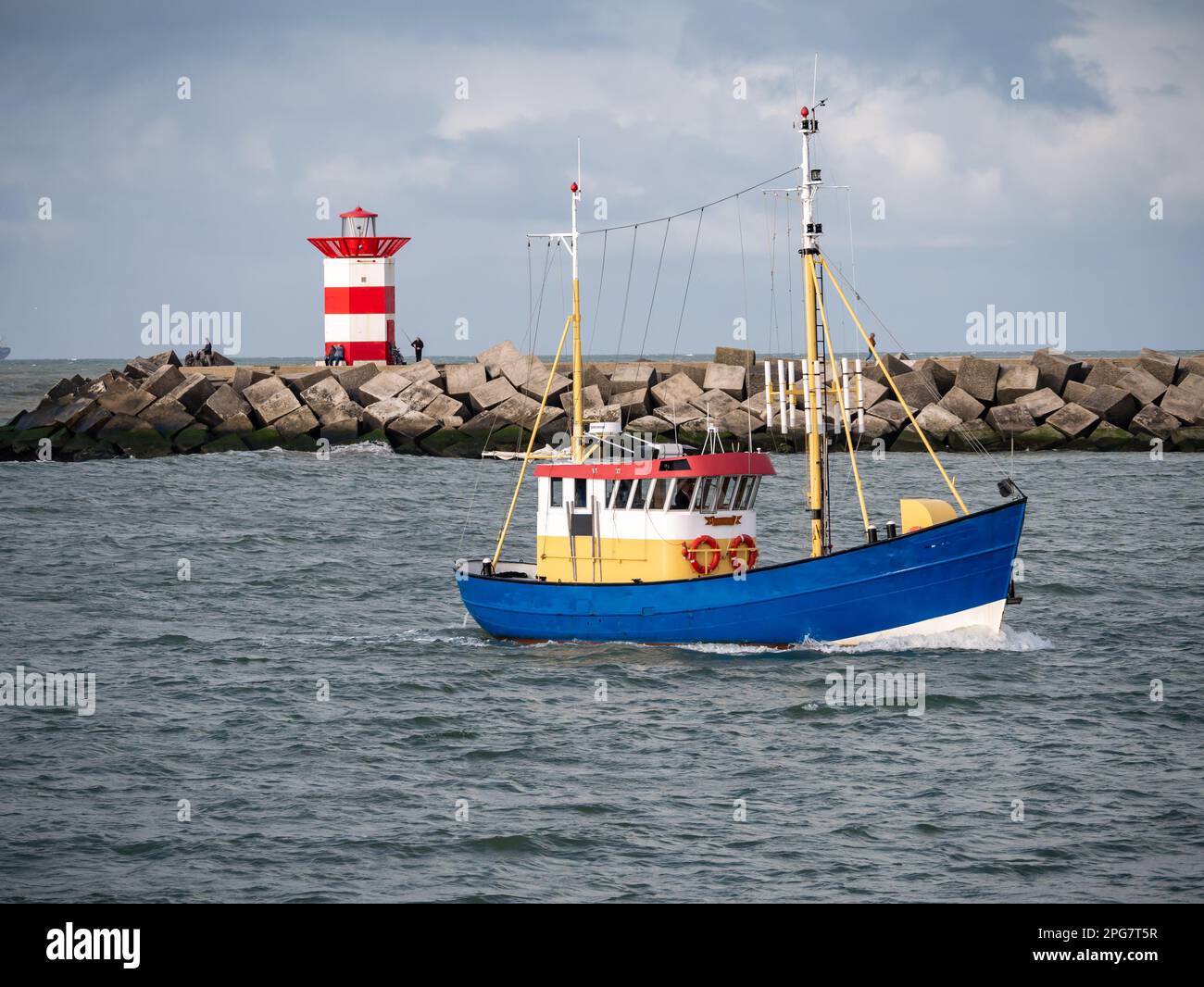 Piccola barca da pesca e molo settentrionale con faro bianco rosso del porto di Scheveningen, l'Aia, Paesi Bassi Foto Stock