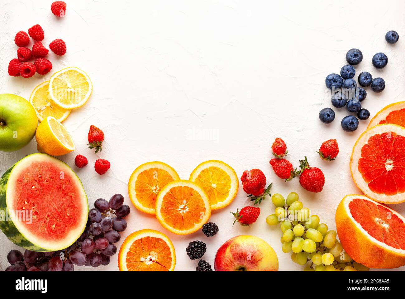 Frutta fresca e frutti di bosco assortiti su sfondo bianco. Mangiare pulito, vita sana. Vista dall'alto. Foto Stock